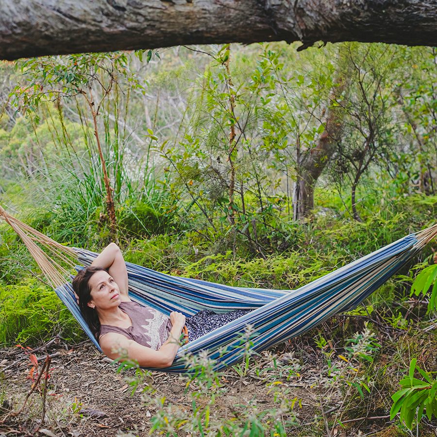 A woman relaxes on a hammock in the forest at Happy Buddha Retreats accessible from Sydney.